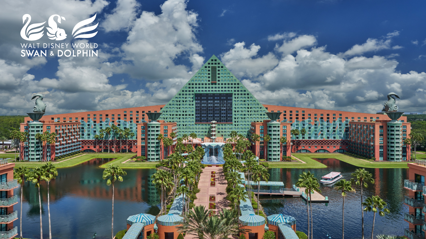A large resort complex with a distinctive green pyramid-shaped central building stands beside a reflective lagoon under a bright blue sky with scattered clouds. The foreground features palm trees, fountains, and walkways leading toward the main entrance. Two sculpted figures sit atop corner structures, framing the central architecture. In the upper left corner, the text "Walt Disney World Swan & Dolphin" appears alongside stylized swan graphics.